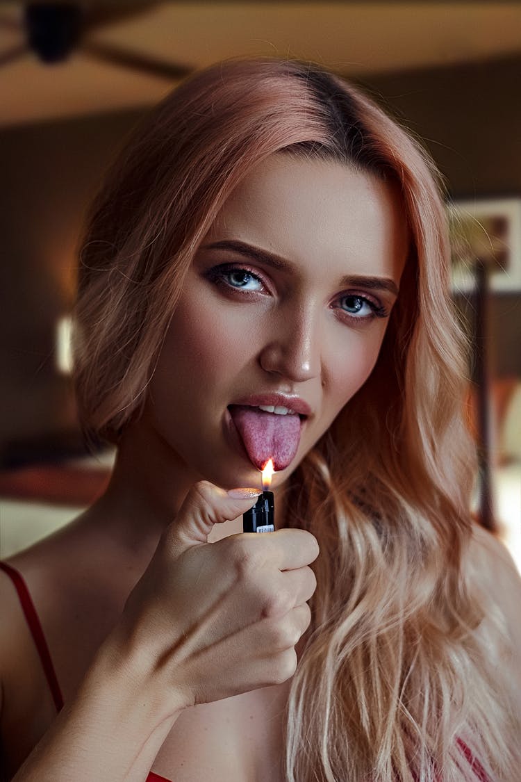 Young Provocative Woman Raising Lit Lighter To Tongue