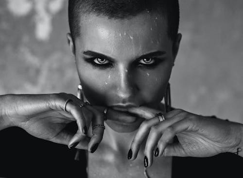 Free Black and white young woman with short hair and wet face biting fingers and looking at camera Stock Photo