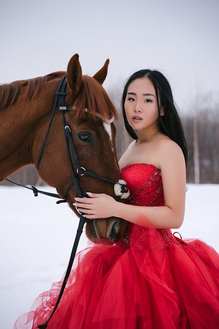 Woman In Red Dress Embracing Muzzle Of Horse