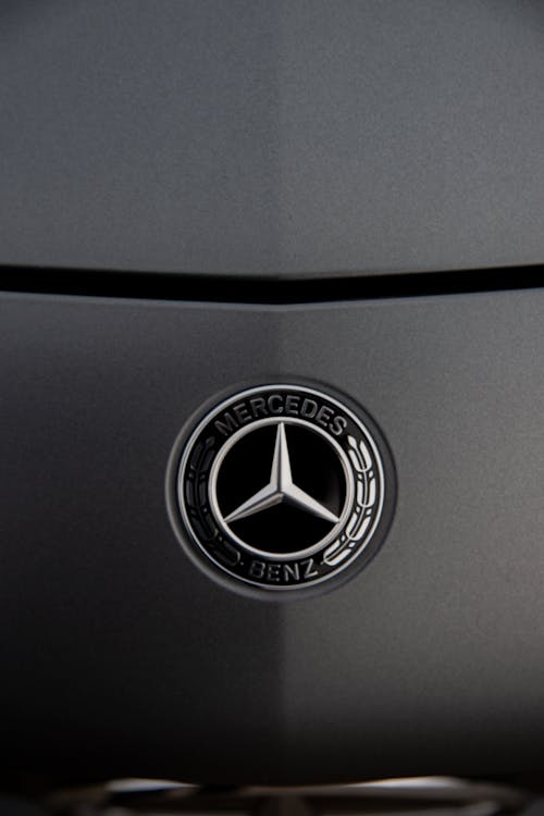 Chrome round shaped logotype of expensive luxury automobile place of dark grey glossy polished car hood