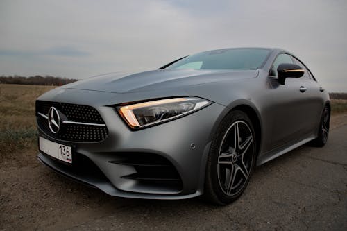 Modern shiny expensive gray auto with switched on headlights parked on roadside in countryside