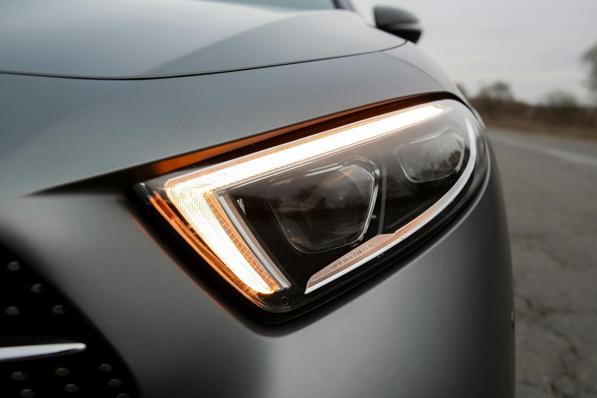 Closeup daytime running lights switched on of modern new polished luxury gray automobile