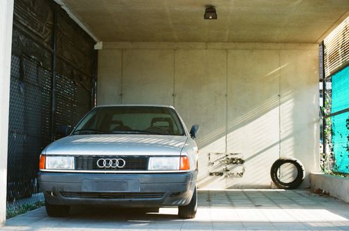 Free Classic car parked in a minimalist garage space with natural sunlight and shadows. Stock Photo