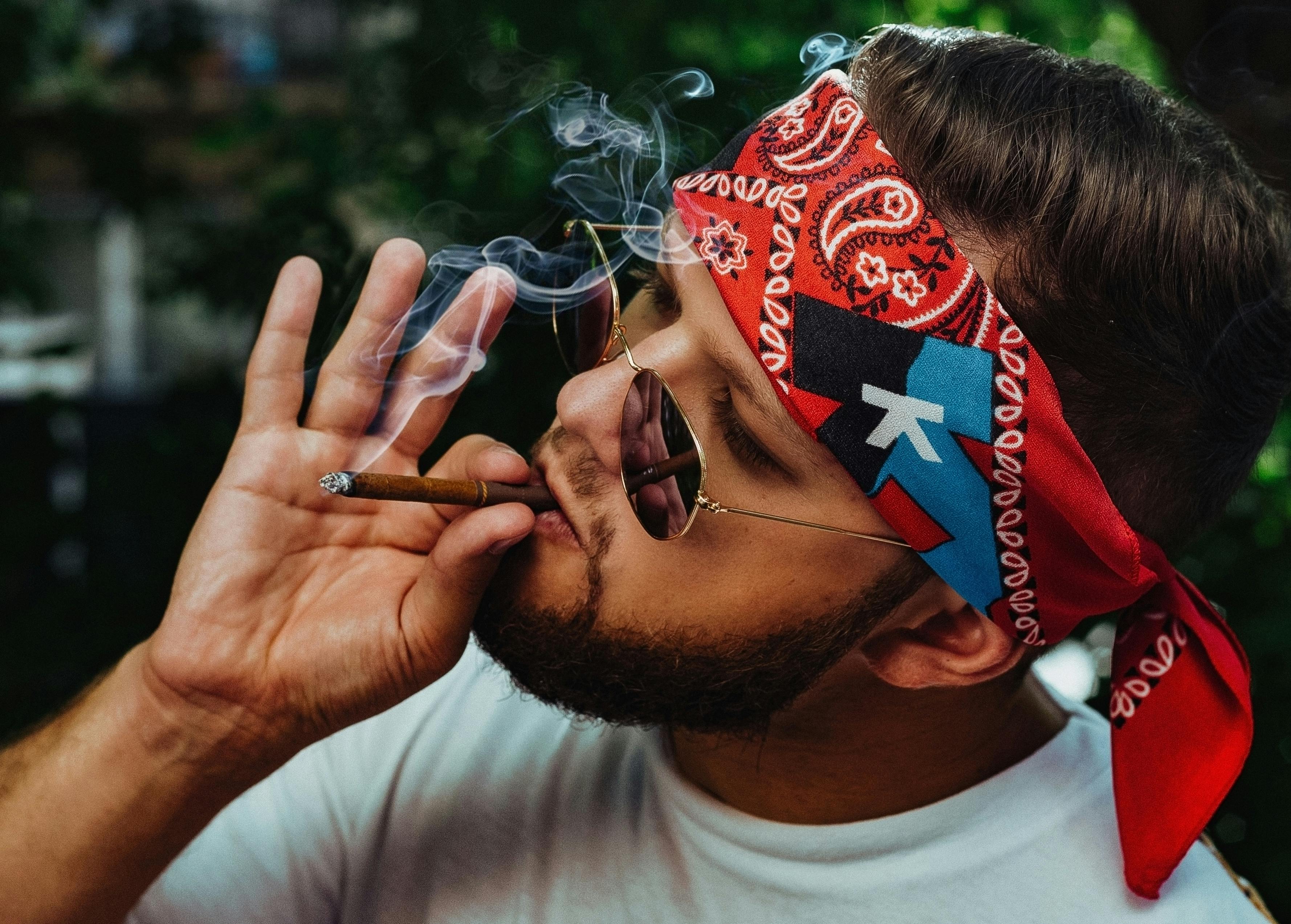 stylish man with headband and sunglasses smoking cigarette