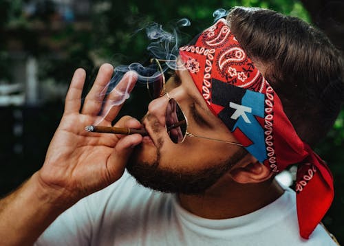 Free Stylish man with headband and sunglasses smoking cigarette Stock Photo