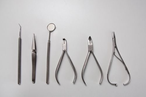 Free Range of metal sterile dental instruments for inspection and treatment on light gray background Stock Photo
