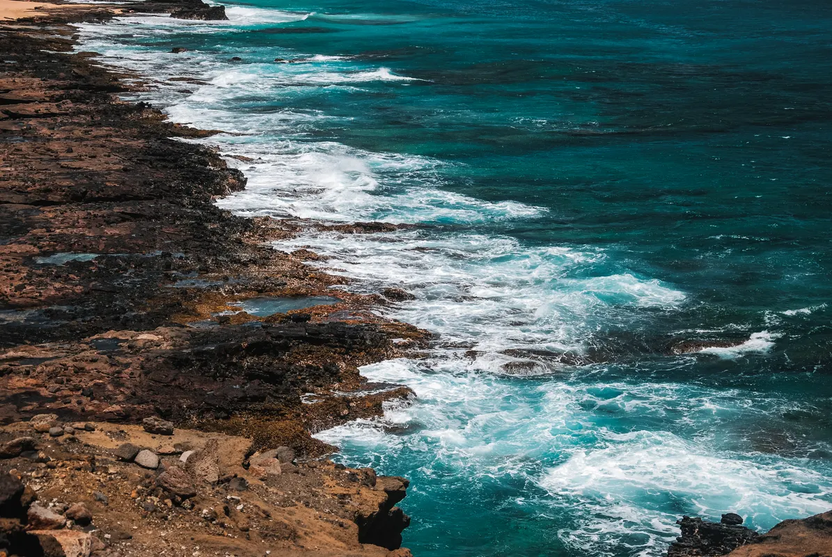 Powerful waves crashing against a rocky Hawaiian coastline, the danger at Queen's Bath in Kauai