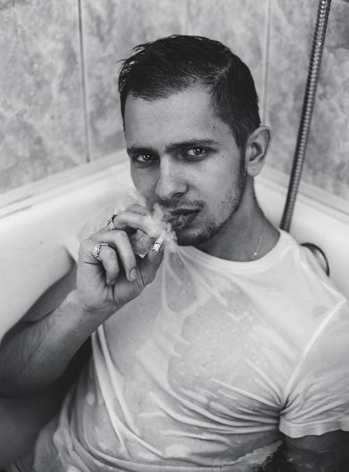 Free Man lying in bathtub smoking cigarette Stock Photo