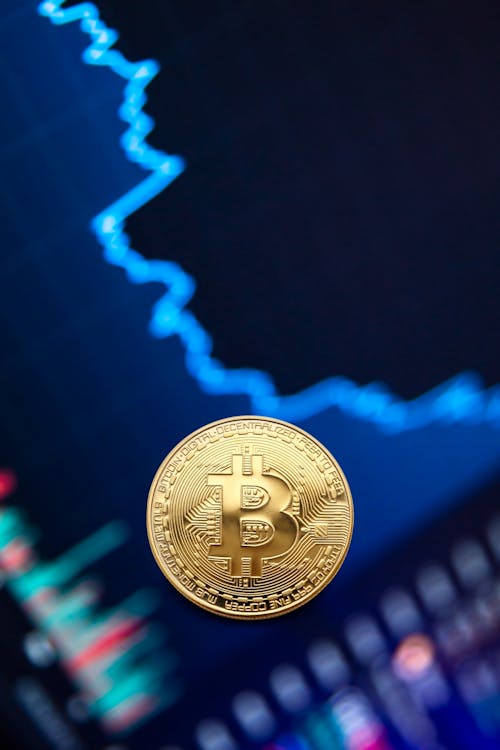 Free Gold bitcoin coin on background of exchange chart Stock Photo