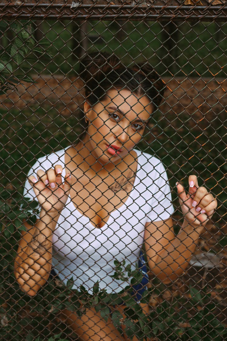 Young Ethnic Woman Holding On Iron Mesh