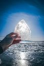 Person reaching out hand with ice against sunlight