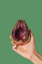 Female showing half avocado with pink glitter