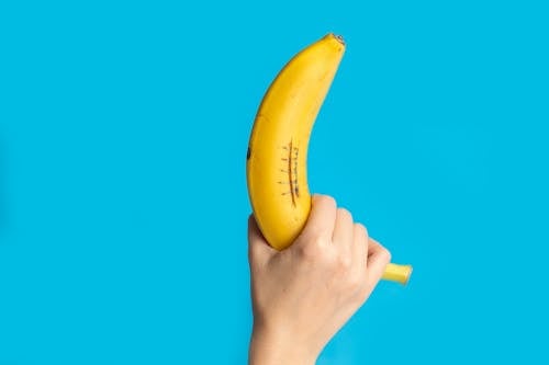 Person showing banana against blue background