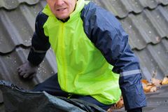 A construction worker wearing safety gear inspects a roof for maintenance.