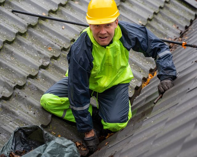 Roofer working safely on a roof Construction worker in a helmet and safety gear on a rooftop