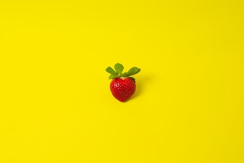 Ripe strawberry on yellow surface