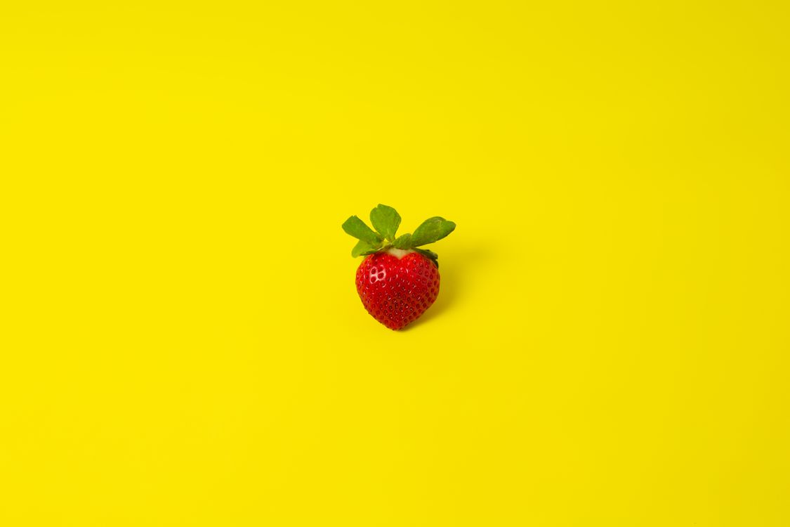Ripe strawberry on yellow surface · Free Stock Photo