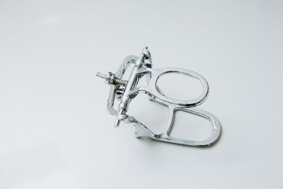 From above of metal dental occluder used for creating denture placed on white background