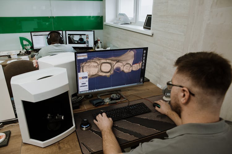 Unrecognizable Man Working On Computer In Dental Clinic