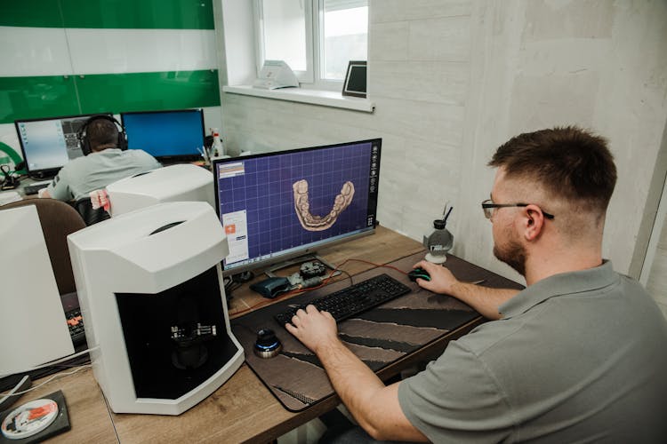 Unrecognizable Specialist Working On Computer In Modern Dental Clinic