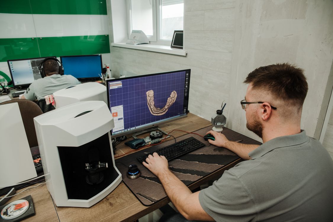 Profissional não identificável trabalhando em computador em ambiente odontológico digital