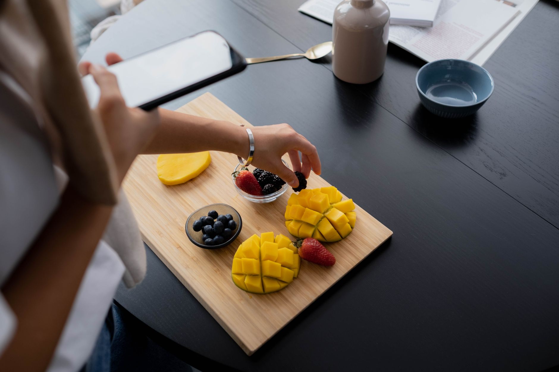 Close-up of a person photographing a colorful fruit platter.