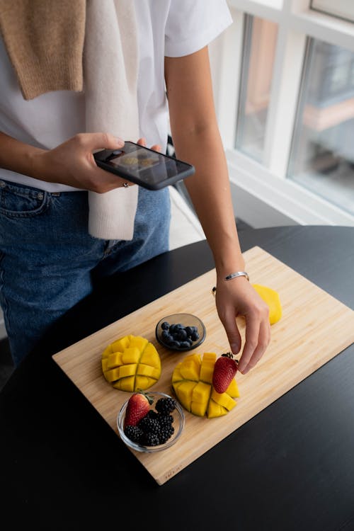 Person Taking Photo of Fruits on Wooden Tray 