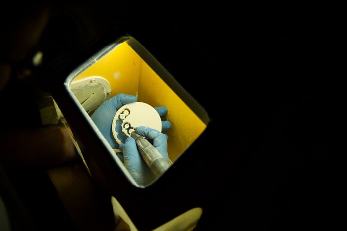Dental laboratory technician crafting a full-arch prosthesis with precision instruments