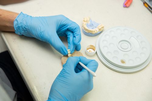 Free From above of crop anonymous orthodontist in latex gloves making fake teeth for denture in modern dental clinic Stock Photo