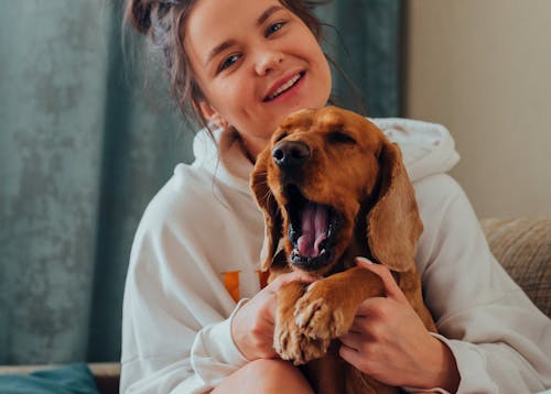 Smiling woman hugging yawning dog