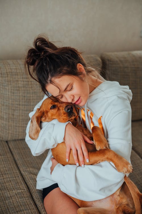 Tender woman hugging obedient dog at home