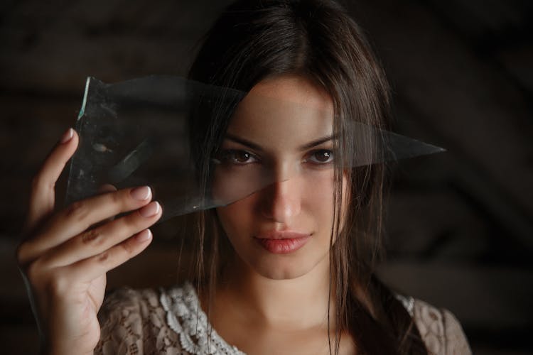 A Woman Holding A Piece Of Broken Glass