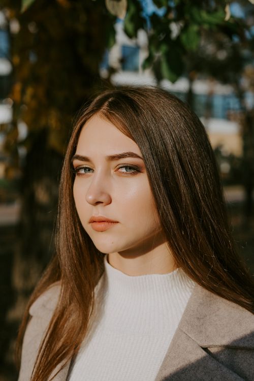 Free Portrait of a young woman with brown hair in a stylish autumn outdoor setting. Stock Photo