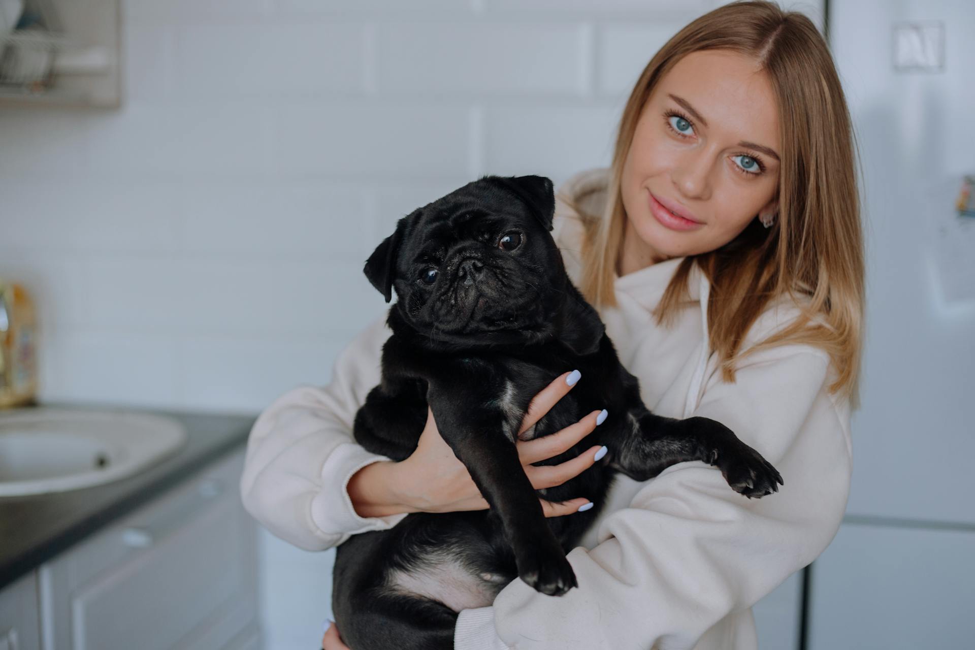 Een vrouw met een capuchon die haar hondje vasthoudt