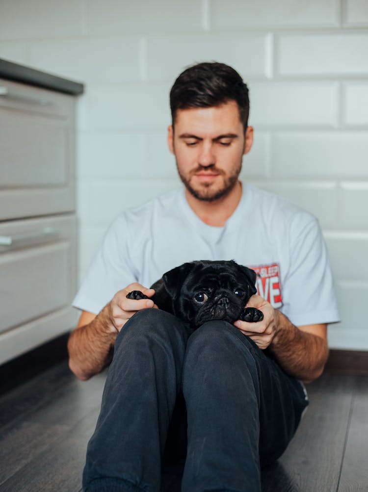 
A Man In A White Shirt With His Pet Pug