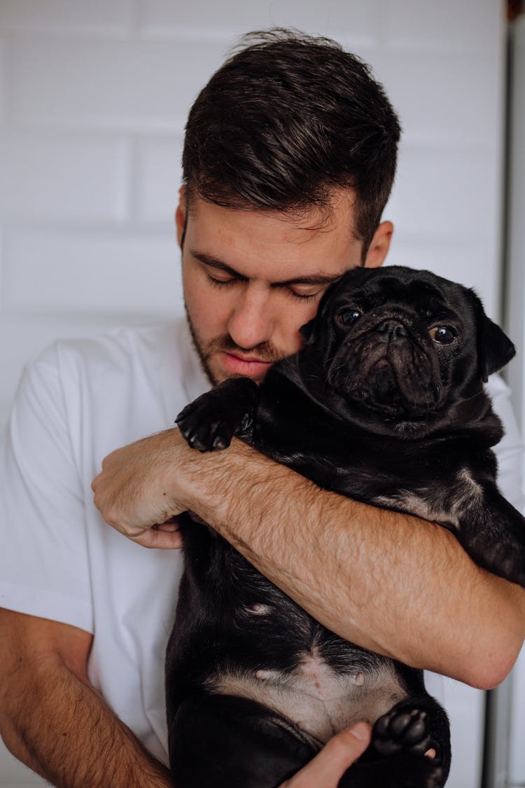 Man With Eyes Closed Cuddling A Pug