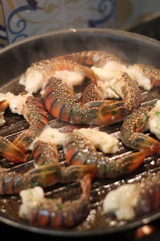 Succulent lobster tails grilling with butter and herbs, emitting aromatic steam.