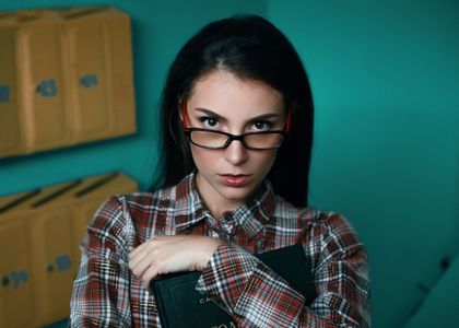 Portrait of a confident woman in eyeglasses holding a book indoors — photo by Ivan Babydov on Pexels