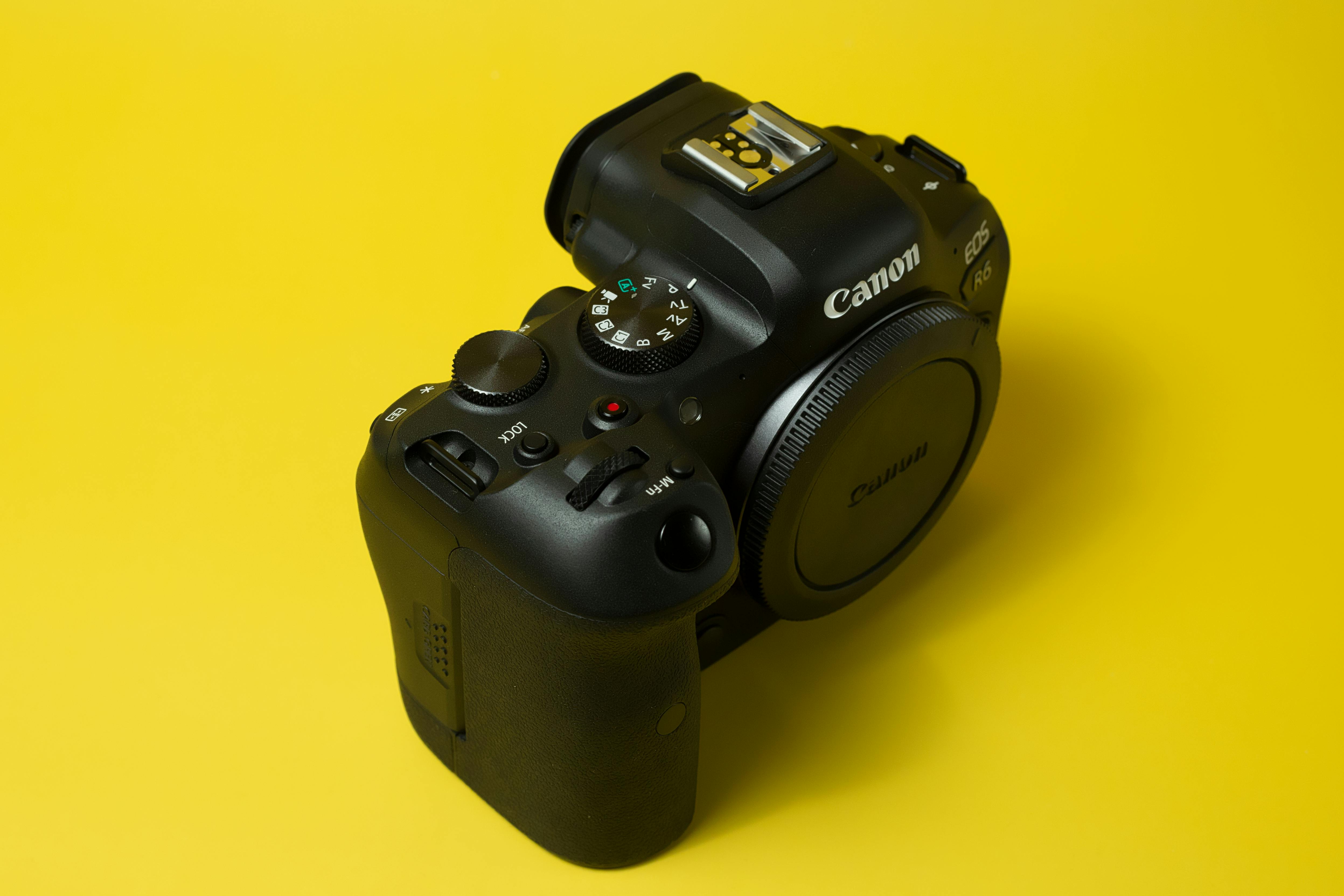 Free Close-up of a DSLR camera displayed on a bright yellow background, emphasizing modern photography tools. Stock Photo