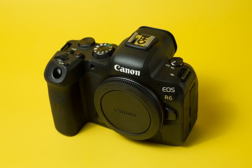 Free Close-up of a black DSLR camera on a vivid yellow background. Stock Photo