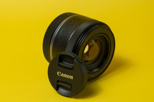 Free Detailed shot of a camera lens with cap on vibrant yellow background. Stock Photo