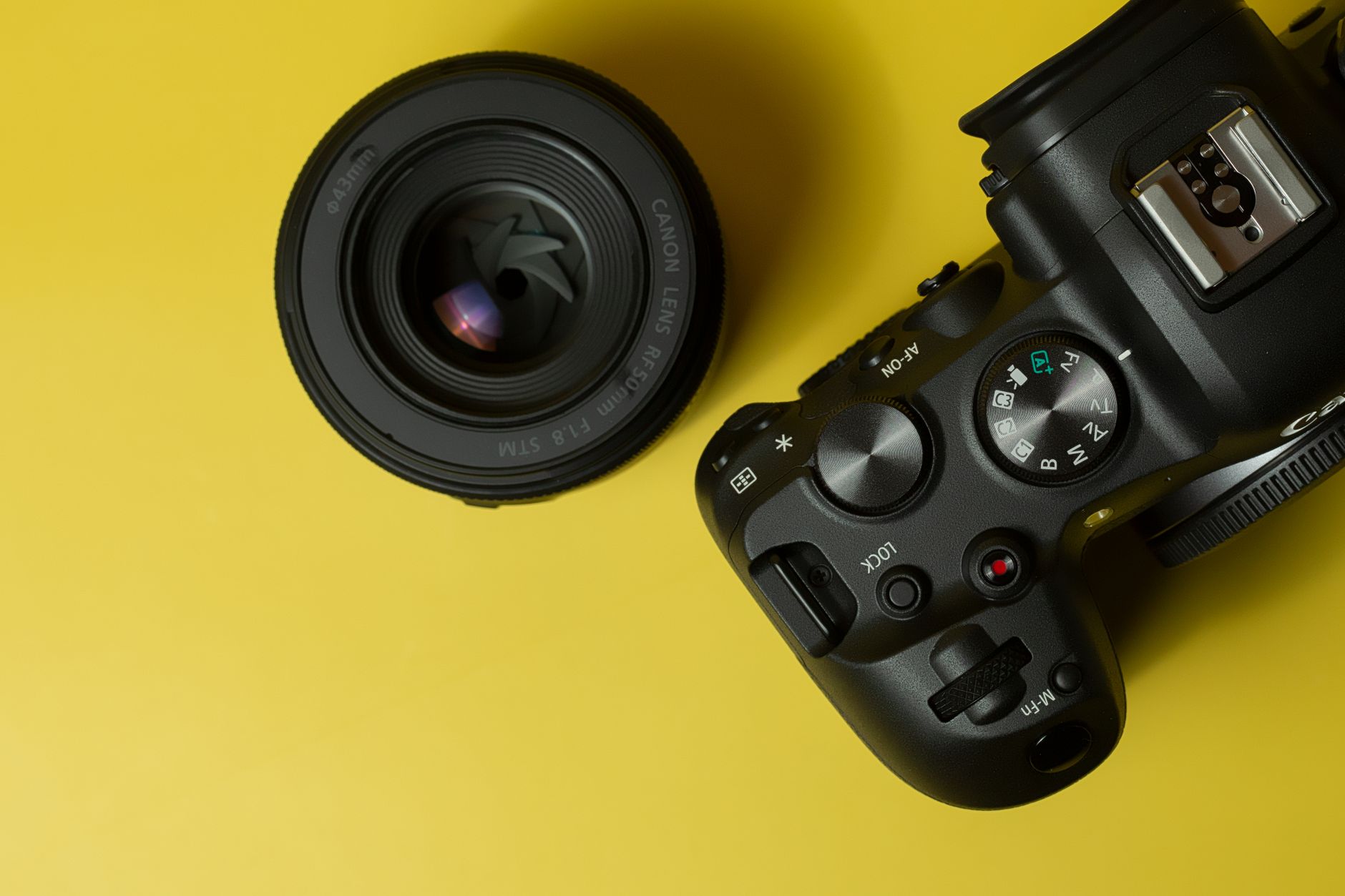Close-up of mirrorless camera and lens against a vibrant yellow backdrop, showcasing modern photography technology.