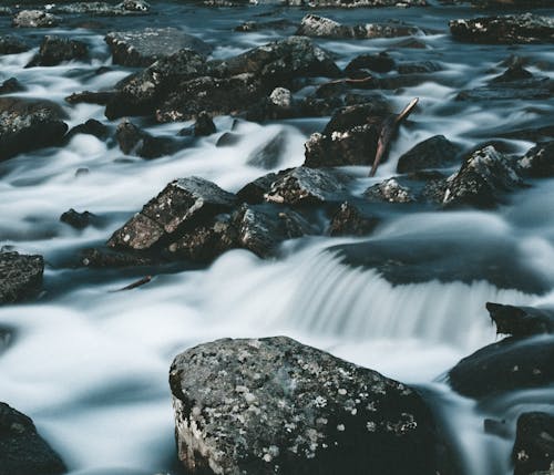 Scenery landscape of fast stream of water with foam flowing through rocky formations in daylight