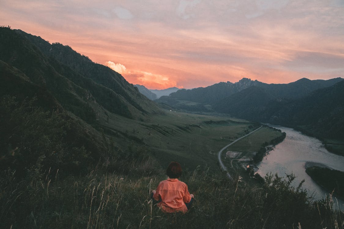 Unrecognizable woman sitting on hill