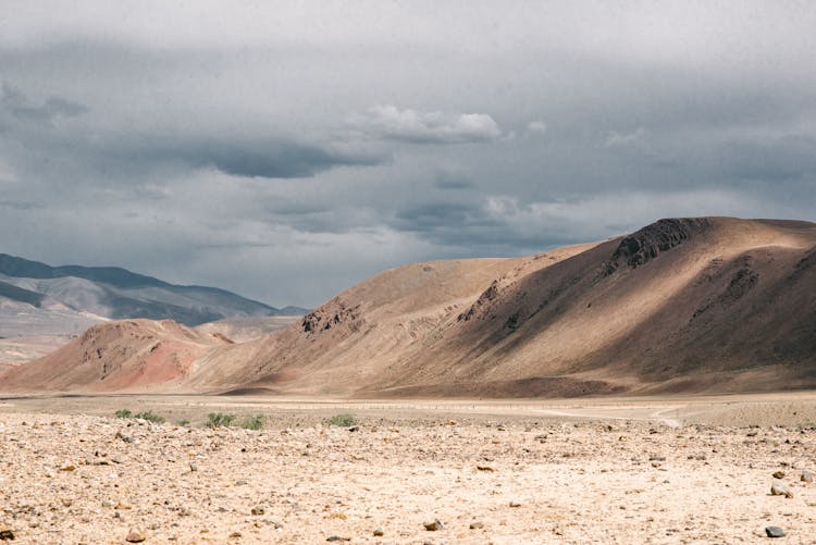 Dry Desert With Hills Under Cloudy Sky