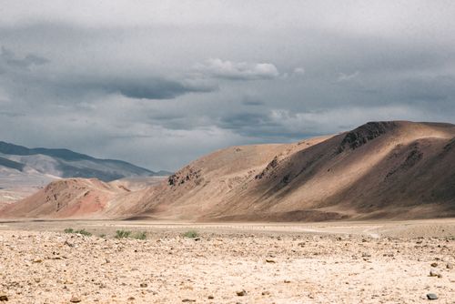 Free Spectacular view of dry desert terrain and hills with dry vegetation under cloudy sky in summer Stock Photo
