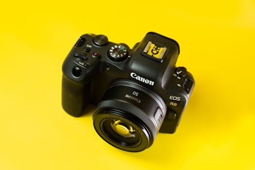 Close-up of a digital camera on a vibrant yellow background, highlighting modern photography equipment.