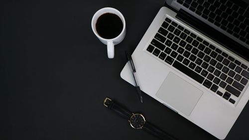 Free A clean workspace with a laptop, coffee, pen, and watch, ideal for productivity and focus. Stock Photo