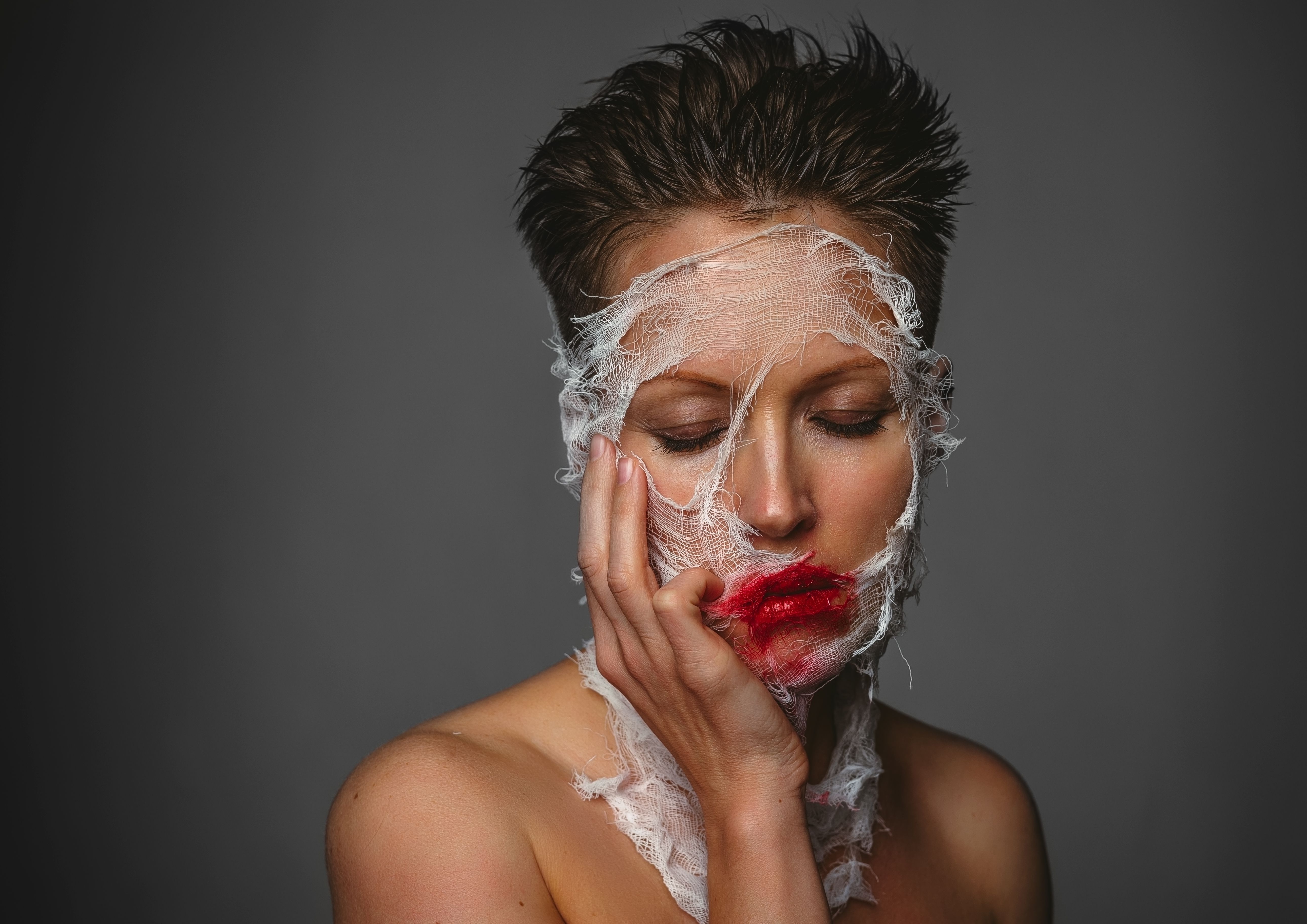 Close-up portrait of a woman with gauze wrap and smeared lipstick showing artistic expression.