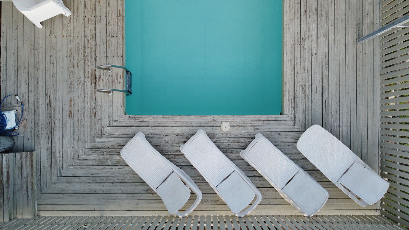 Top-down view of sunbeds beside a small pool